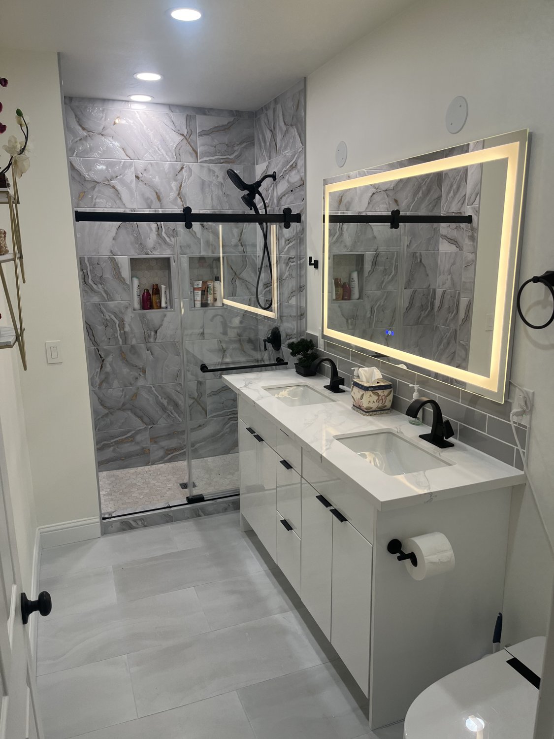 Completed Tigard bathroom with tiled glass shower, double vanity and illuminated mirror